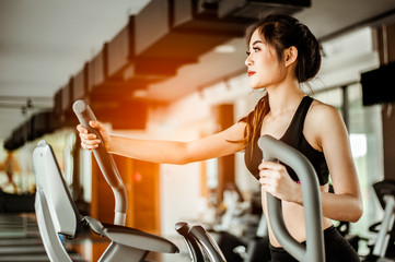 Fitness woman cardio workout on an elliptical.people working out on an elliptical trainer in gym. - obrazy, fototapety, plakaty