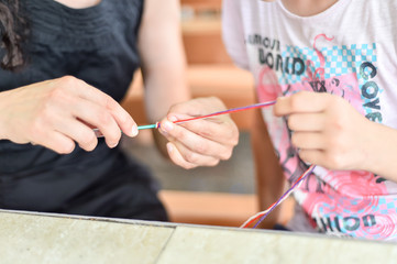 Hands of an adult and hands of a child knitting together