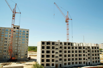 Picture of construction cranes building two big houses