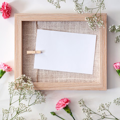A wooden mockup frame surrounded by white and pink flowers