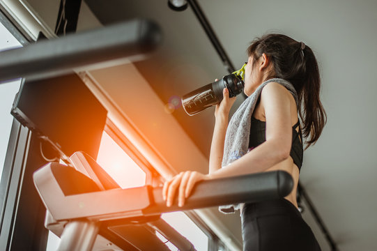 Young woman at treadmill drinking water.Young woman at treadmill drinking .protein shake.
