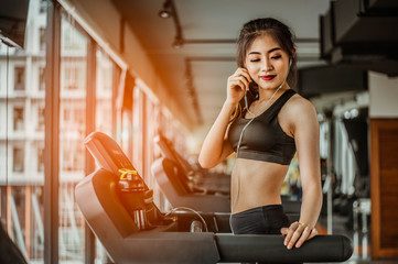 Portrait of Fitness woman running on treadmill in gym listening to music.exercising concept.fitness and healthy lifestyle.