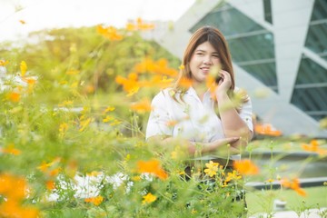 Portrait of pretty Asian fat woman posing in the flower garden in happiness.