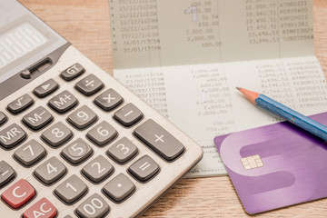 Calculator, cash card, pencil, bankbook Put on a wooden table.