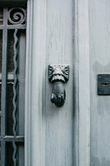 Vintage handle for knocking on the door in the form of a hand. Entrance to the apartment building.