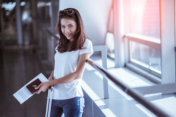 Young woman pulling suitcase in modern airport terminal. Travelling guy with his luggage while waiting for transport. Rear view. Copy space