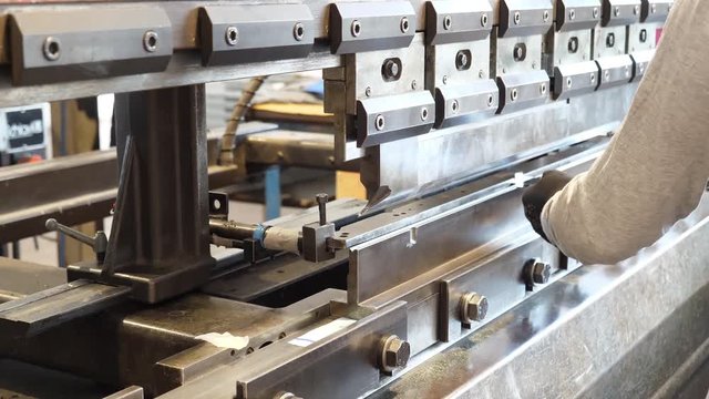 Man working a sheet metal on CNC hydraulic press brake. 4K UHD