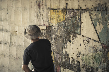 Young man clean the walls by painting white over the old cement wall.