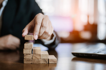 plan and strategy in business.risk concept.hand of man has piling up and stacking a wooden block.Businessman Building The Success.