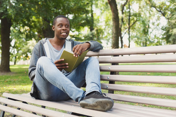 Fototapeta premium African-american student reading a book outdoors