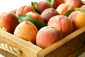 Bunch of ripe freshly picked organic peaches in pile on wooden tray of farmers market. Peach harvest heap. Healthy vegan raw snack. Clean eating concept. Cropped shot, background, top view, flat lay.