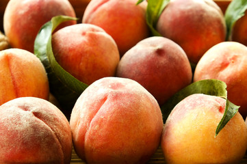 Bunch of ripe freshly picked organic peaches in pile on wooden tray of farmers market. Peach harvest heap. Healthy vegan raw snack. Clean eating concept. Cropped shot, background, top view, flat lay.