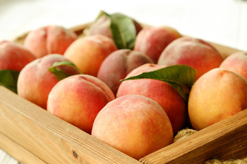 Bunch of ripe freshly picked organic peaches in pile on wooden tray of farmers market. Peach harvest heap. Healthy vegan raw snack. Clean eating concept. Cropped shot, background, top view, flat lay.