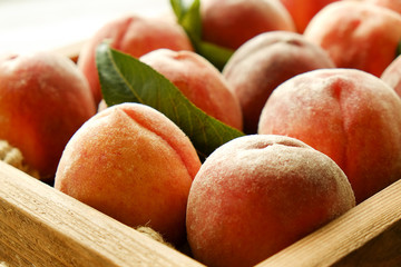 Bunch of ripe freshly picked organic peaches in pile on wooden tray of farmers market. Peach harvest heap. Healthy vegan raw snack. Clean eating concept. Cropped shot, background, top view, flat lay.