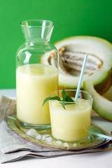 smoothies melon on a green background, glass bottle and slice next to, summer drink, cocktail