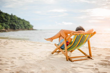 Woman relaxing on beach, looking at sea. Copy space.