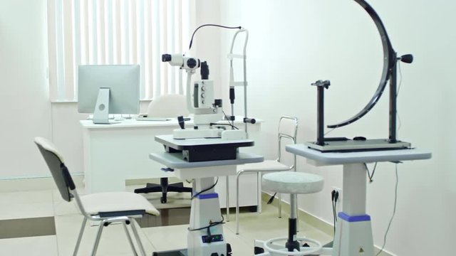 Tracking shot of empty exam room in eye care clinic with modern optometric equipment