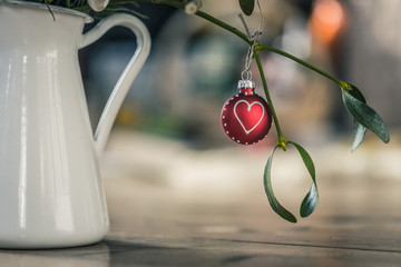 Weihnachtskugel mit Herzsymbol an Mistelzweig