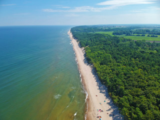 Aerial view on baltic sea water with clean sand beach and forest