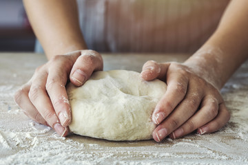 Female hands are kneading dough
