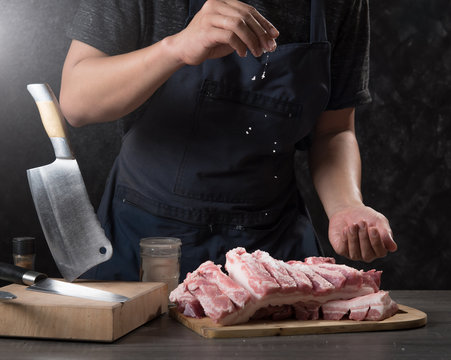 Chef cook pours salt on pork or beef meat,concept of cooking