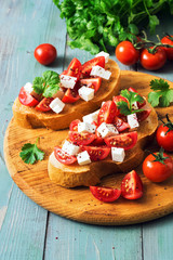 A sandwich with tomatoes and cheese. Italian traditional bruschetta with tomatoes on a rustic green table. Selective focus.