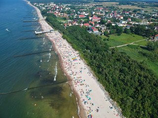 Aerial view on a sea with breakwaters, beach, trees and small city