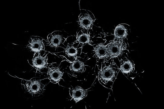 Broken glass multiple bullet holes in glass isolated on black
