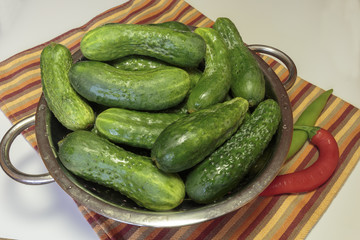 Fresh cucumbers with drops of water in a colander, gherkin as a vegan food.