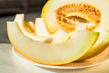 Half melon and melon slices on white plate close