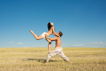 Young guy and girl doing acrobatic stunts against a clear blue sky. Sport. Healthy lifestyle.