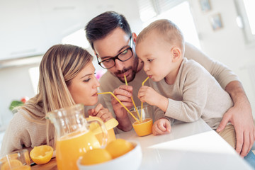 Cheerful young family making orange juice