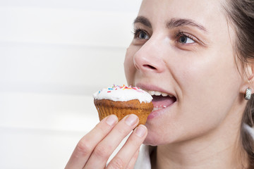 Young girl biting cupcake closeup.