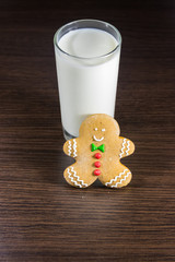 Gingerbread man and glass of milk on dark wooden table