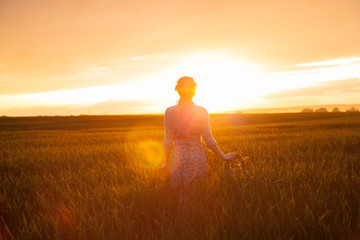  the girl is walking around the field at sunset