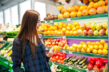 Shopping woman looking at the shelves in the supermarket.  Portrait of a young girl in a market store at fruits and vegetables section.