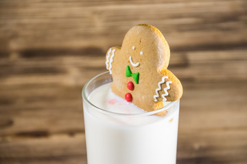 Gingerbread man in glass of milk on dark wooden table
