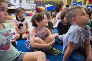 Students listening to their teacher in a kindergarten classroom. 