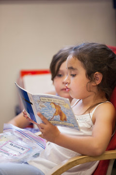 Two students reading a book in a kindergarten classroom. 