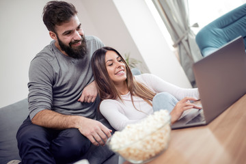 Young couple relaxing on sofa with laptop