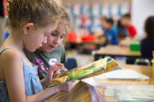 Two students reading a book in a kindergarten classroom. 