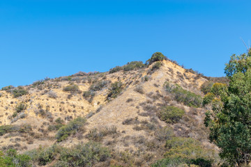 Fototapeta na wymiar Dry hillsides in the mountains of Southern California on hot summer day with room for text in the sky