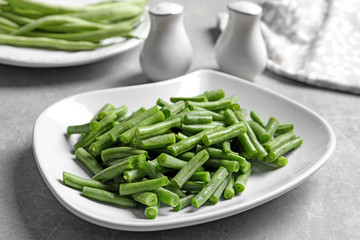 Plate with fresh cut green French beans on table, closeup