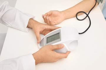 Young doctor checking patient's blood pressure in hospital