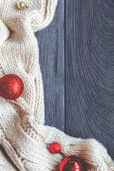 Christmas frame decorated with knitted scarf on grey rough wooden background. Traditional rustic decor for new year holidays. Flat lay, top view, copy space.