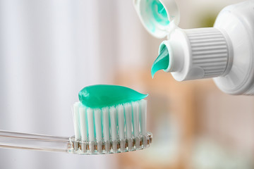 Applying paste on toothbrush against blurred background, closeup