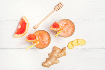 Grapefruit smoothie with honey and ginger on white wooden background