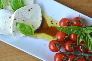 Italian Caprese salad. Close up of mozzarella cheese and cherry tomato salad with Balsamico vinegar, olive oil and basil top view