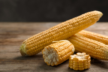 Tasty ripe corn cobs on wooden table