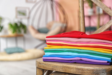 Stack of colorful t-shirts on chair in living room
